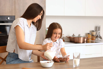 Happy mother with her little daughter having breakfast in kitchen - Powered by Adobe