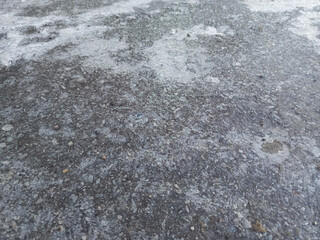 Black ice. Dangerous weather conditions. Thin layer of ice on asphalt, road. Background, place for text. Weather forecast. Frost. Winter. Frozen footprint on ice. Slippery road. Bad weather.