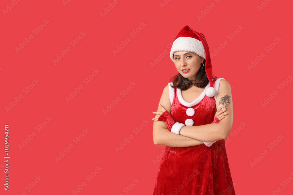 Wall mural Young woman in Santa Claus costume on red background