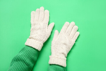 Female hands in warm gloves on green background, closeup