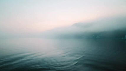 A tranquil scene of a blue body of water with a misty veil shrouding the horizon, Misty veil shrouding the horizon