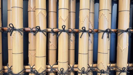 Fototapeta premium Beautifully crafted bamboo, decorated with intricate patterns, is arranged and tied neatly in a traditional Japanese style, showcasing elegance and skill in craftsmanship that captivates all.