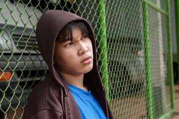 Portrait of Asian teenage prisoner behind metal bars in prison cell looking for freedom....