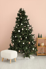 Beautiful Christmas tree with shelving unit and pouf near pink wall