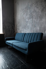 A cozy blue couch rests against a textured gray wall in a serene living space illuminated by natural light
