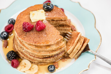A stack of pancakes cut with a fork and berries on top