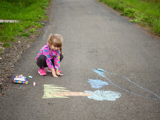 Fototapeta premium girl draws with colored chalk on the asphalt