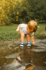 Toddler putting hands and feet in mud puddle