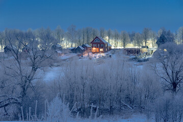 A cozy wooden house glowing warmly in the middle of a snow-covered village during twilight,...