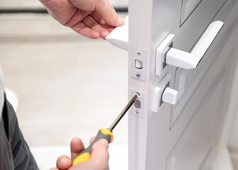 Locksmith using a screwdriver to install or repair a door lock, focusing on the precise work of...