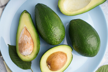 Plate with fresh ripe avocados on white background, closeup