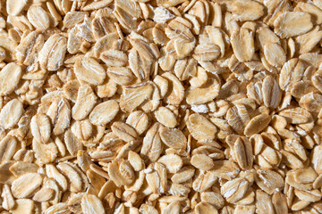 Uncooked Oat Flakes background - Top View, Flat Lay. Scattered Dry and Raw Oat Flakes. Healthy Breakfast and Diet Eating Ingredients