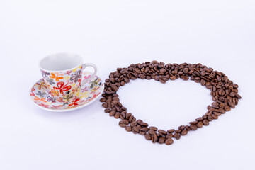 Heart Made of Coffee Beans with a Cup on White Background