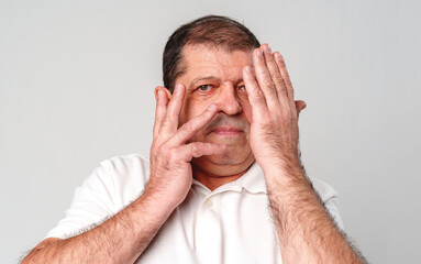 Man covering half of his face with hands while looking at the camera indoors