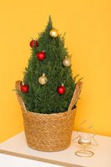 Dresser with Christmas tree in basket and candle near orange wall