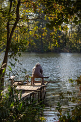 A woman sits on a dock by a lake, enjoying the peaceful scenery