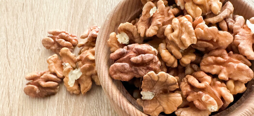 Walnut kernel halves, in a wooden bowl. Close-up, from above on colored background. Healthy eating Walnut concept. Super foods with copy space.