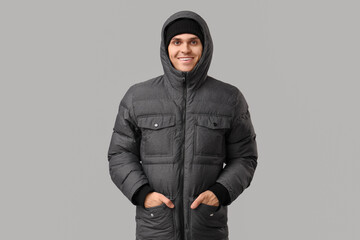 Young man in stylish puffer jacket on grey background