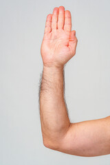 Hand raised in greeting against a plain background