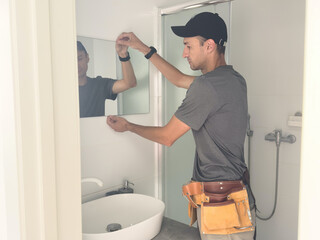 Handyman installing a mirror in bathroom