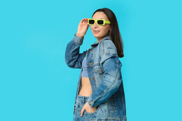 Fototapeta premium Beautiful young happy woman in stylish denim clothes on blue background