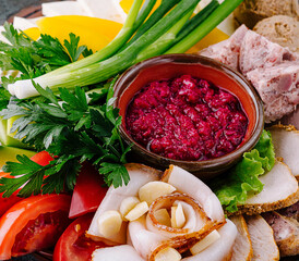 Appetizing sliced salo with garlic served with greens and horseradish sauce