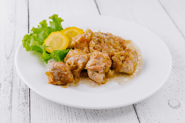 Pork meat with onion sauce is served on white plate with lettuce and zucchini slices