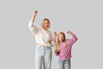 Beautiful woman and her cute daughter in stylish sweaters on grey background