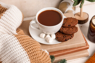 Beautiful composition with books, warm clothes, winter decor and cup of cacao on white wooden background
