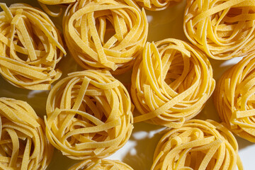 Uncooked Egg-Based Fettuccine Pasta: A Culinary Canvas of Ribbon-Shaped Macaroni, Creating a Lively and Textured Background for Gourmet Cooking. Dry Pasta. Raw Macaroni - Top View, Flat Lay