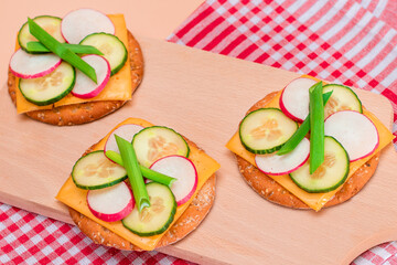 Light Breakfast. Quick and Healthy Sandwich. Fresh Cucumber and Radish with Green Onions and Cheese on Crispy Cracker on Wooden Cutting Board