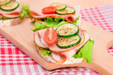 Light Breakfast. Quick and Healthy Sandwiches. Rice Cake with Ham, Tomato, Fresh Cucumber and Green Salad on Wooden Cutting Board