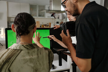 Director using computer and making plan of shooting with crew in studio