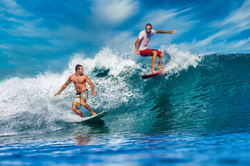 Two male surfers on a blue wave at sunny day