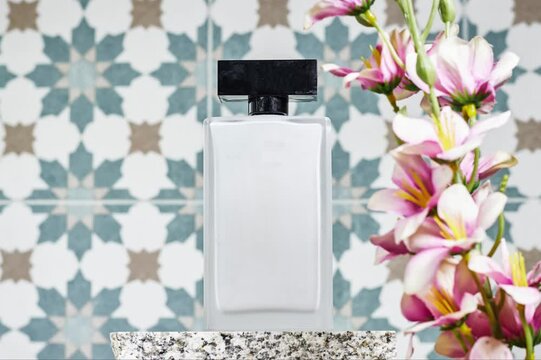 gray bottle of perfume mable on stone plate. Fragrance presentation with daylight. Trending concept in natural materials with flowers. Women's and men's
