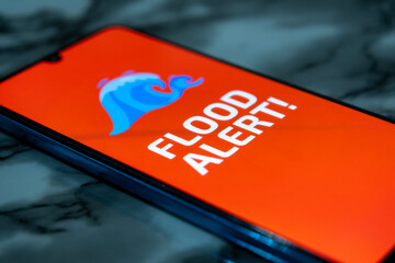 “Flood Alert” message on the smartphone screen. Emergency alert. Smartphone screen and warning...