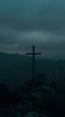 Naklejka premium A hauntingly beautiful scene of a cross silhouette against a dark, cloudy sky at dusk, conveying solitude and serenity. It exudes contemplation and peace in a moody twilight landscape