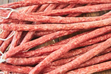 Dried hunting sausages lie on a wooden surface. Meat production.