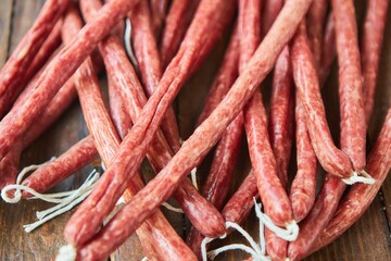 Dried hunting sausages lie on a wooden surface. Meat production.