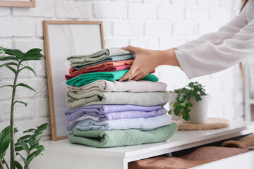 Young woman putting stack of clothes into drawer at home, closeup