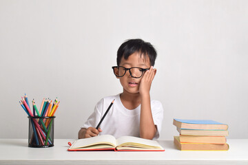 Portrait of an Asian boy studying isolated on a white background. The child is dizzy with his...