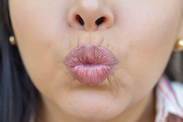 A close-up image of a female face, focusing on her pouty lips and the tip of her nose.