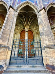 Obraz premium The photograph captures a close-up of an old medieval gate, crafted from wood and metal, set in the charming streets of a historic European city.