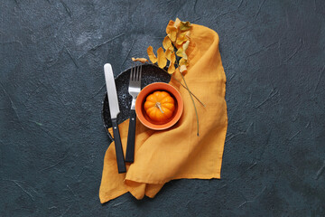 Beautiful table setting with fresh pumpkin and autumn leaves on dark background