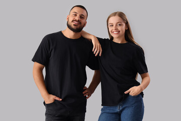 Young couple in stylish black t-shirts on grey background