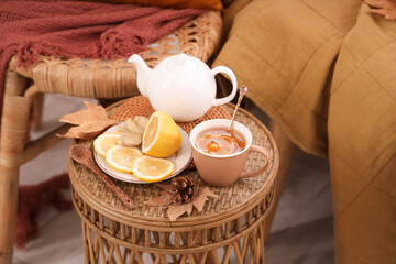 Teapot, cup of green tea and plate with ginger and lemon on coffee table in room