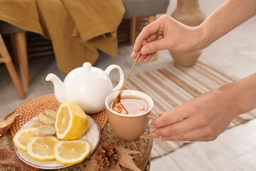 Female hands stirring green tea on table in room. Closeup