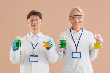 Chemists with flasks on beige background
