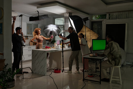 Team of operators shooting content with model in professional studio