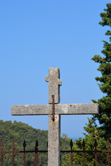 Old stone cross with letters INRI against blue sky